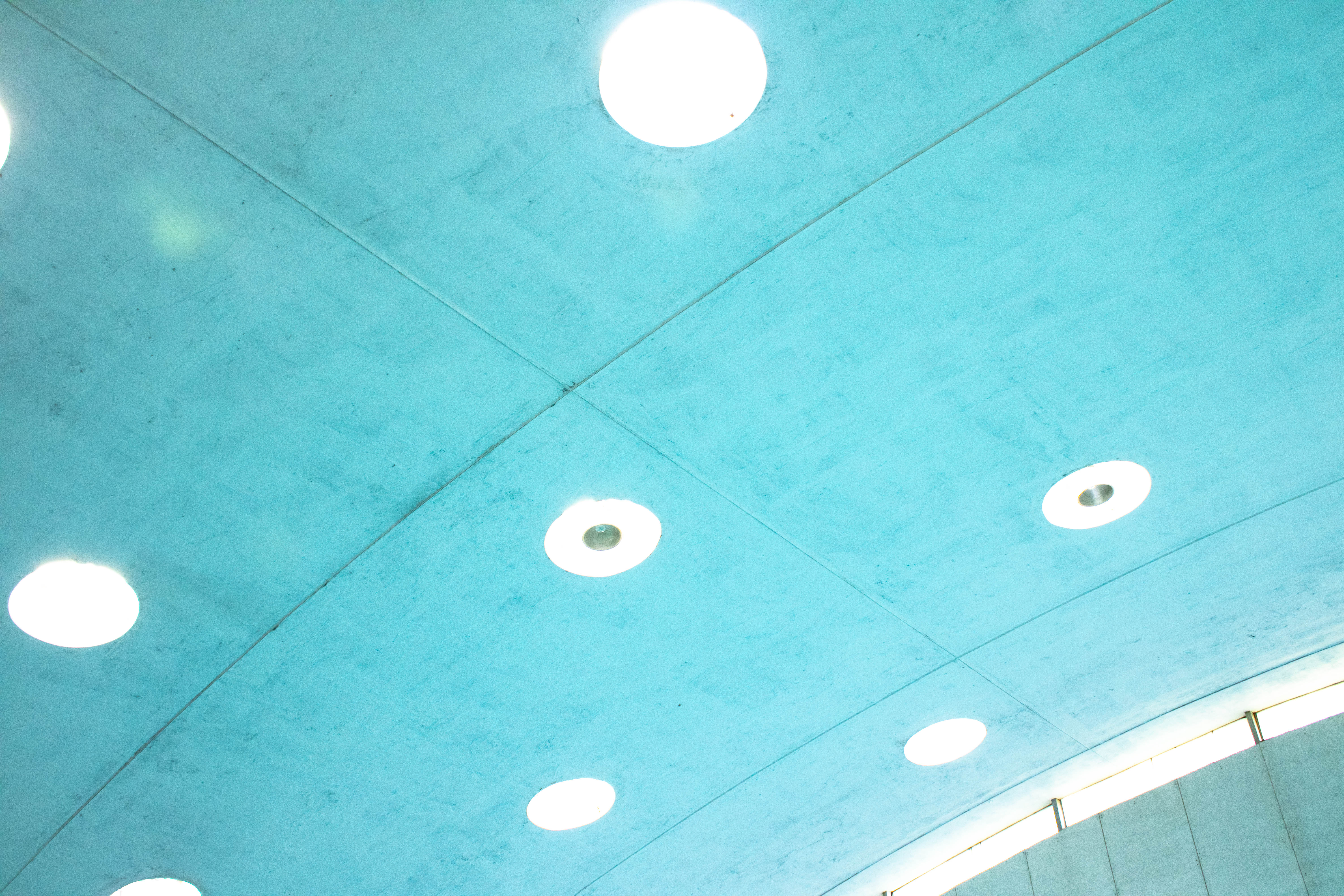 Image of the ceiling of the pool area which is bright blue with circular white lights and light gray lines.